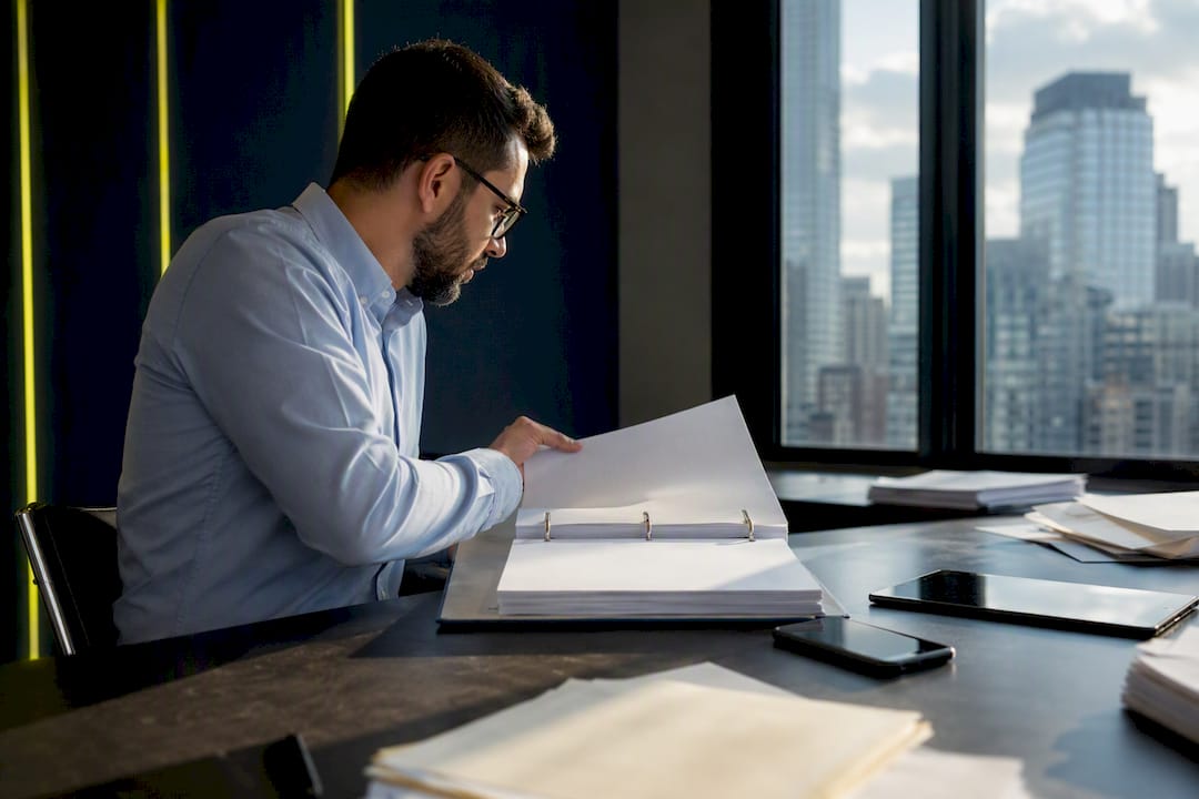 Hands flipping binder in a compliance officer’s workspace